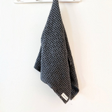 House of Holabox charcoal organic cotton waffle tea towel hanging on a wall hook with a rustic textured finish