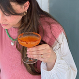 House of Holabox Chilli Margarita cocktail in a coupe glass with a spicy salt rim held by a woman in a pink sweater