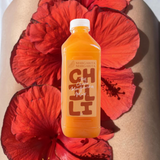 House of Holabox Margarita Margarita Chilli Margarita Mix in a clear bottle against vibrant red hibiscus flowers.