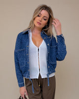 House of Holabox Cleo Denim Cropped Jacket in blue with a subtle animal print pattern. Features button closure and chest pockets.