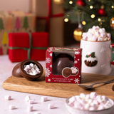 House of Holabox Cocoba milk chocolate bomb with mini marshmallows in festive red packaging on a wooden board.