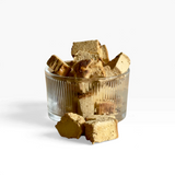House of Holabox Proper Treats Co. freeze-dried coffee cheesecake bites in a ribbed glass bowl on a tan background.