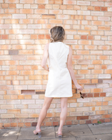 House of Holabox Sabine denim vest dress in cream cotton with princess seams, viewed from the back against a brick wall