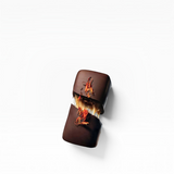 House of Holabox dark chocolate truffle broken in half, revealing a gooey caramel center and topped with edible flowers.