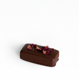 House of Holabox dark chocolate truffle topped with dried rose petals against a soft pink background