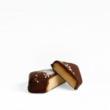 House of Holabox vegan dark chocolate truffle with a creamy nut center and sea salt garnish on a light background.