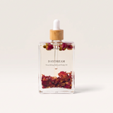 House of Holabox Soaked Body Bar Daydream nourishing bath and body oil in a glass bottle with dried flower petals.