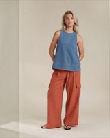Model wearing House of Holabox pale blue sleeveless cotton denim tunic with stitch detail and rust cargo trousers.