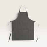 House of Holabox Ecology Rye khaki cotton kitchen apron with adjustable straps and metal stud detailing.