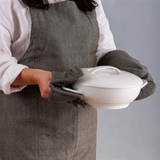 House of Holabox Ecology Rye khaki cotton apron with matching oven mitts holding a white ceramic casserole dish