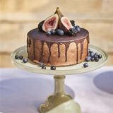 House of Holabox Ecology Torte glass cake stand in sage green holding a chocolate cake topped with fresh fruit.