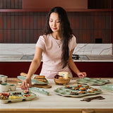 House of Holabox Ecology Selvedge oyster plate in Mine green stoneware on a table with a woman serving appetizers