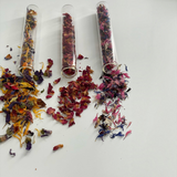 Three clear glass test tubes with cork stoppers containing colorful dried flower petals in yellow, red, and mixed pink and blue hues, with some petals spilled out, showcasing The Peel Thing Edible Flower Sprinkles.