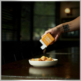 House of Holabox Fancy Hank’s Chicken Salt being sprinkled over a bowl of roasted potato wedges