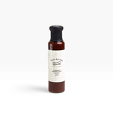 House of Holabox Finns Kitchen chunky barbeque sauce in a glass bottle with a black wax seal on a white background