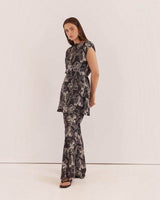 Model wearing House of Holabox Fiora tunic top with boat neck and waist tie in a black and white floral print