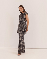 Model wearing House of Holabox Fiora tunic top with boat neck and waist tie in a black and white floral print