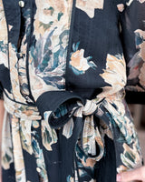 House of Holabox Missy belted mini dress in black with a warm neutral floral print, featuring a self-tie waist belt.