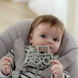 Baby holding a grey House of Holabox Little Drop silicone teether with textured geometric shapes for soothing relief