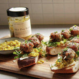 House of Holabox Hot Dog Relish served on toasted bread with meatballs and arugula on a wooden board