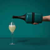 House of Holabox Huski champagne cooler in dark green stainless steel pouring sparkling wine into a glass