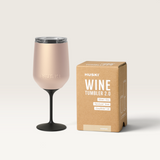 House of Holabox Huski Wine Tumbler 2.0 in powder pink with a black stem and lid next to its cardboard packaging.