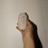 House of Holabox Ivy Ila French Pear hand cream in a beige 100g bottle held in a hand against a white tiled background.