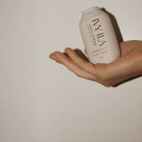 House of Holabox Ivy Ila Lychee and Peony hand cream in a beige bottle held in a hand against a neutral background