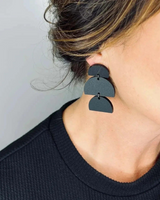 House of Holabox Izzy dangle earrings featuring matte black sculptural acrylic shapes worn by a woman.
