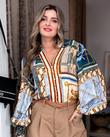 House of Holabox Jacquline shirt with equestrian print in teal, ochre, and blue, worn with tan trousers.