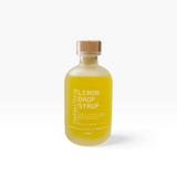 House of Holabox The Peel Thing lemon drop syrup in a frosted glass bottle with a wooden stopper on a stone surface.