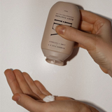 House of Holabox Ivy Ila lime and coconut body custard being squeezed from a beige bottle onto a hand