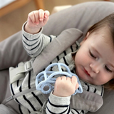 Baby holding a light blue House of Holabox Little Drop silicone teether in a car shape for soothing teething relief