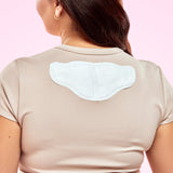 House of Holabox Lula self-warming body patch applied to the back of a woman wearing a beige t-shirt for pain relief.