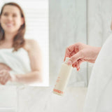 House of Holabox Mamave Mumma’s Oil bottle held by a woman in a bathroom mirror reflection for pregnancy skincare