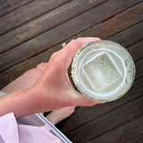House of Holabox Margarita Margarita mix in a salt-rimmed glass with a large ice cube held by a person outdoors