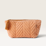 House of Holabox melon velvet toiletry bag with quilted chevron pattern, zip closure, and decorative side tassel.