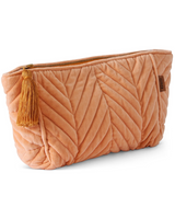 House of Holabox melon velvet toiletry bag with quilted chevron pattern, zip closure, and decorative tassel detail.