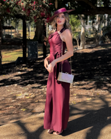 House of Holabox model wearing a dark cherry red Morgan & Taylor boater hat with a matching jumpsuit outdoors.