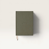 House of Holabox Jour Studio linen planner in olive green with embossed text and a small ribbon bookmark
