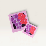 House of Holabox Orchid Crush square greeting cards with purple orchid and red flower illustrations on stone surface