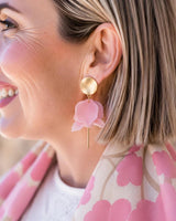 House of Holabox Olivia earrings featuring matte gold discs and light pink layered flower petals on a woman