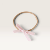 House of Holabox Snuggle Hunny baby headband featuring a soft pink velvet bow on a stretchy nude nylon elastic band
