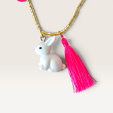 House of Holabox rabbit necklace featuring a white bunny charm and vibrant neon pink tassel on a gold-toned bead chain