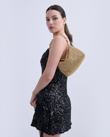 House of Holabox Reverie metallic gold beaded chain bag worn over the shoulder by a model in a black sequin dress.