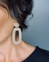 House of Holabox Riley dangle earrings featuring a beige organic oval shape worn on a model with an updo hairstyle.
