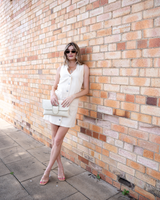 House of Holabox Sabine denim vest dress in cream cotton with contrast stitching, worn by a model against a brick wall