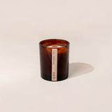 House of Holabox saide. large amber glass soy candle with a wood wick and clove and sandalwood label