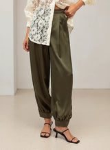 House of Holabox Satin Moment Pant in pesto green featuring a high-rise waist, blouson leg, and cuffed ankles.