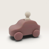 House of Holabox Little Drop silicone toy car in dusty rose with a removable cream-colored driver figure.
